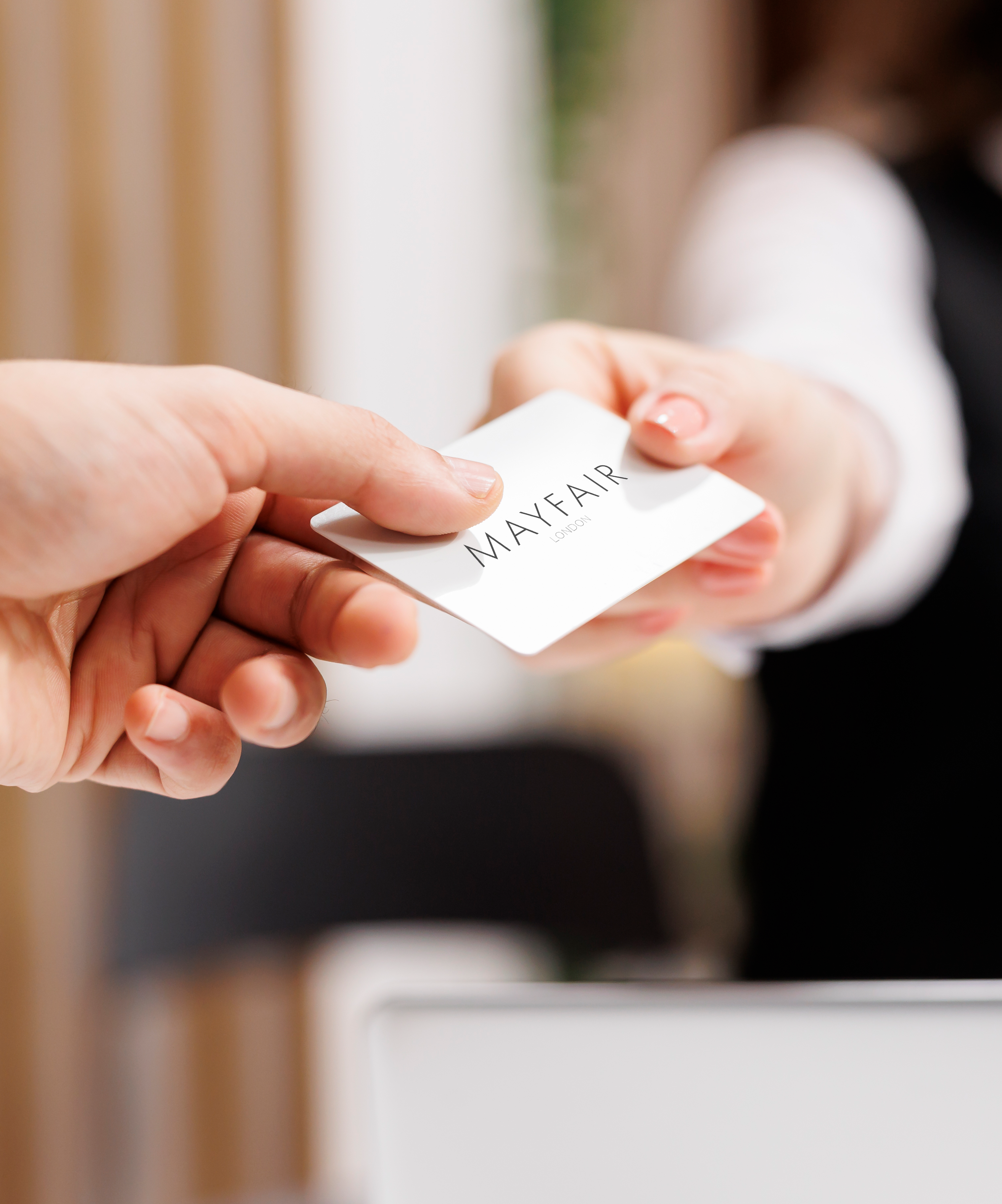 A person passing another person a Mayfair giftcard