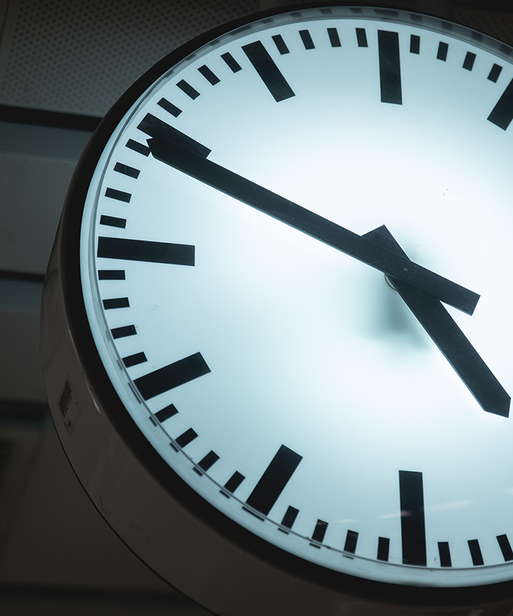 Countdown clock with a bright face on a dark background, hand approaching the hour