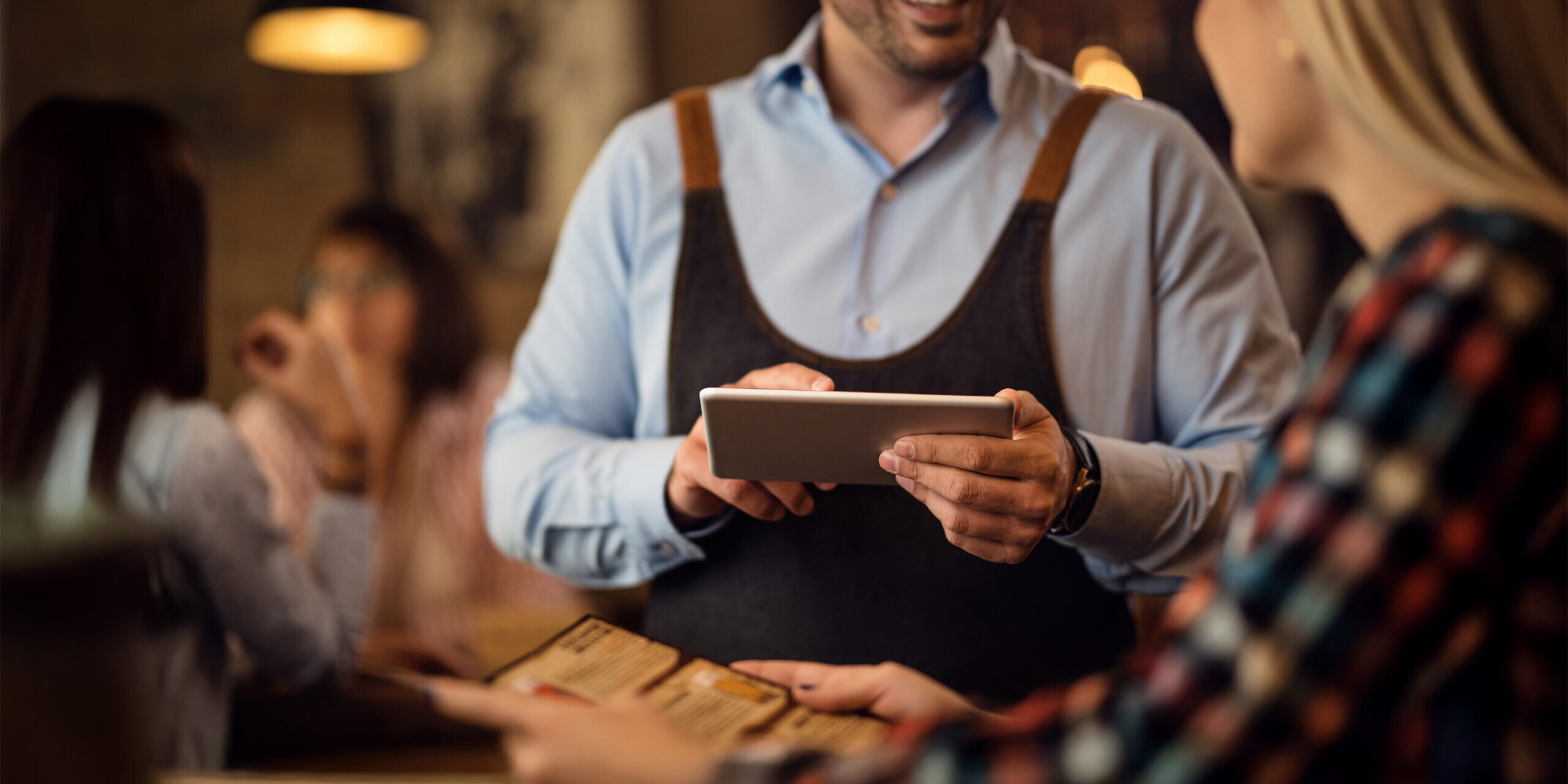 Close-up of waiter taking an order using a tablet