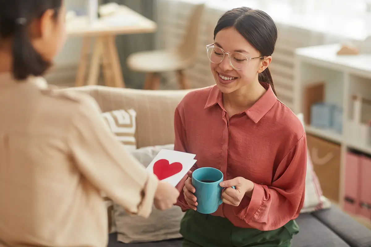 Girl giving a Mother's Day gift card to her mum