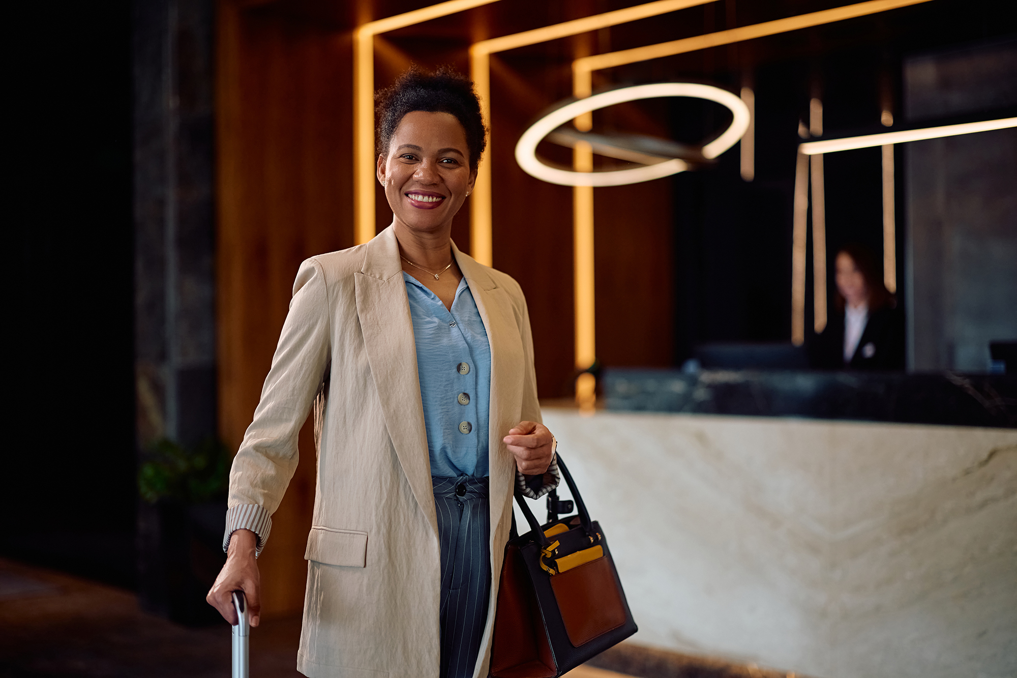 Hotel guest arriving at reception with luggage, representing the seamless guest journey supported by VoucherCart VRM and OPERA Cloud integration.